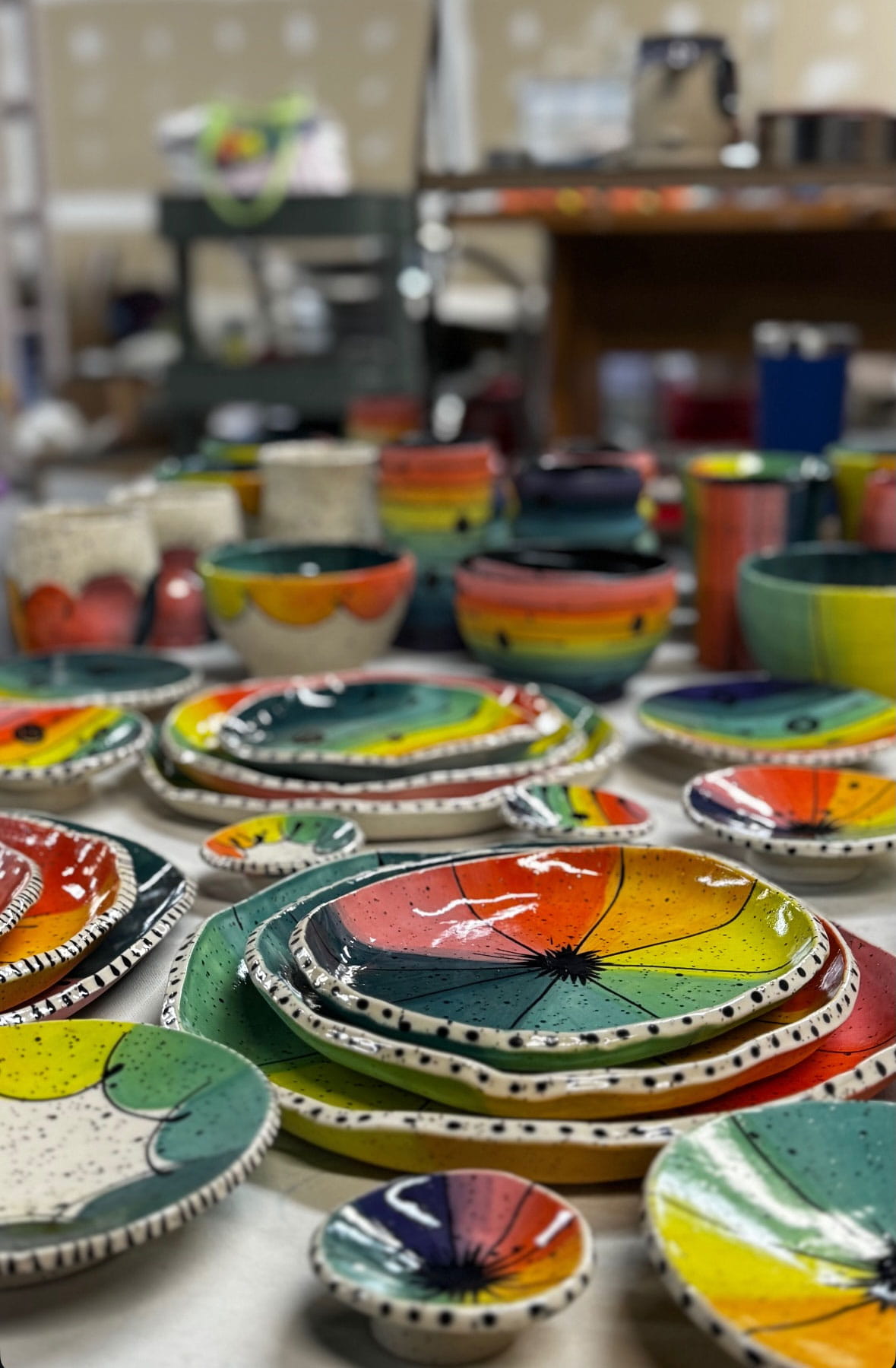 Pink and colorful handmade ceramics arranged on studio shelves